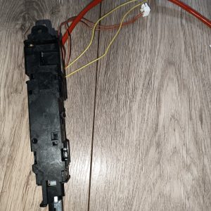 Black electrical switch module with red and yellow wires and white connector headers resting on a wooden floor, shown from the side.