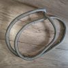 Three gray braided cables coiled on a wooden floor with small metal hooks attached along their length