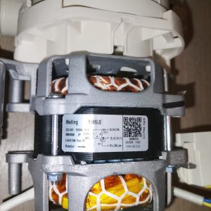 Close-up of a small electric motor with visible copper windings and a gray housing, and a label showing model YW50-2E and technical details on its side.