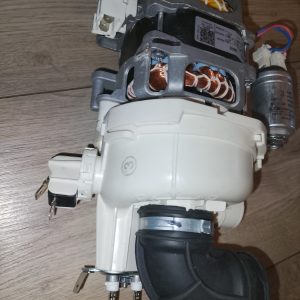 Disassembled electric motor or appliance drive unit with copper windings, white plastic housing, wiring harnesses, and a capacitor laid on a wooden floor as seen from the side view, showing internal components.