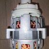 Close-up of an electric motor rotor with white plastic mounting and exposed copper windings
