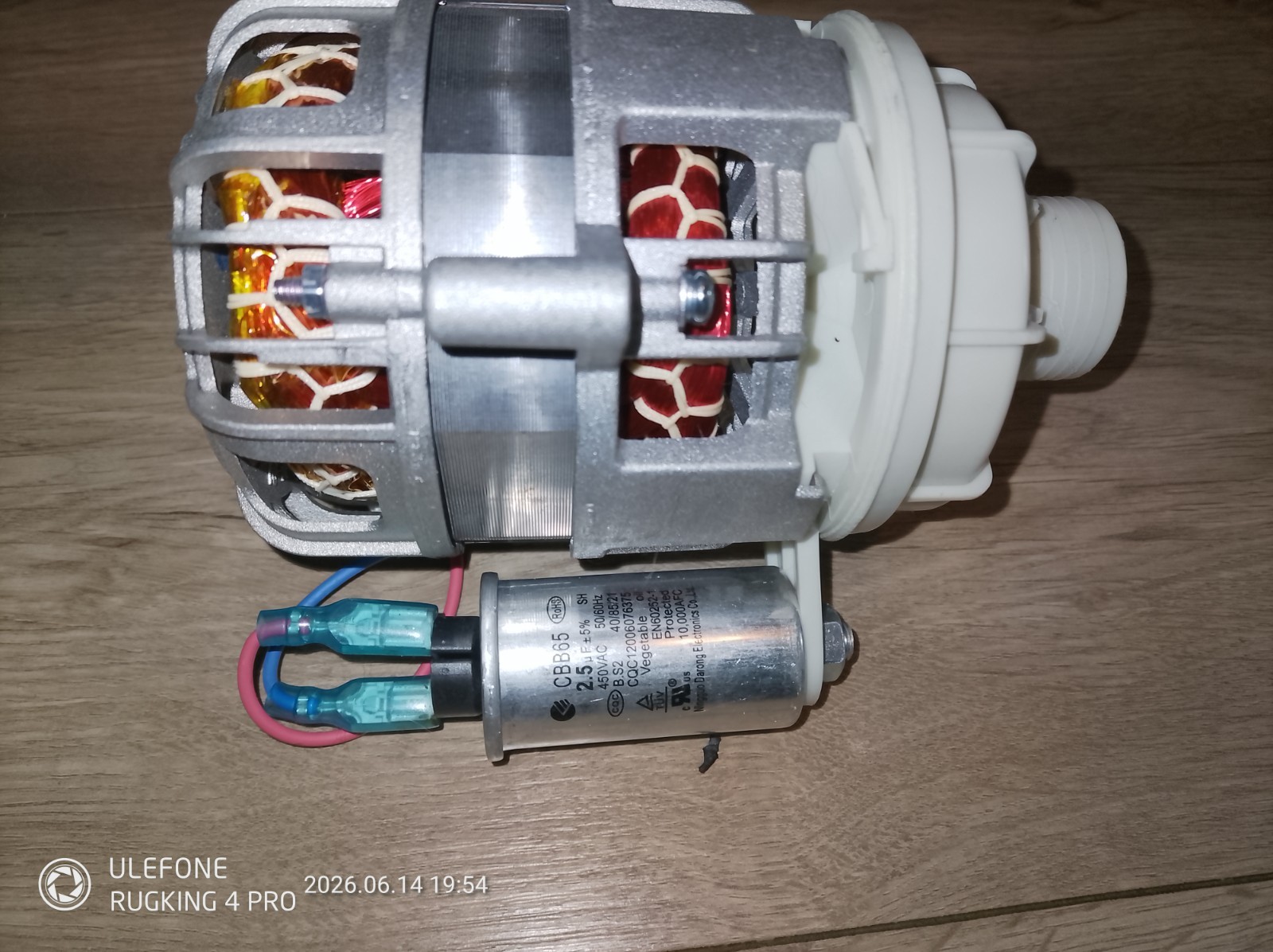 s-l1600-1147.jpg DC electric motor assembly with a metal housing and white plastic coupling, wires connected at the bottom, laid on a wooden surface.