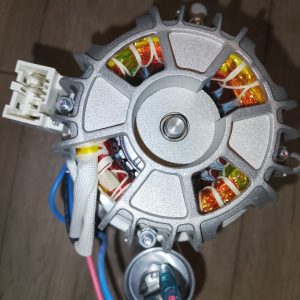 Close-up of an electric motor rotor with exposed copper windings and a white multi-pin connector on the side.