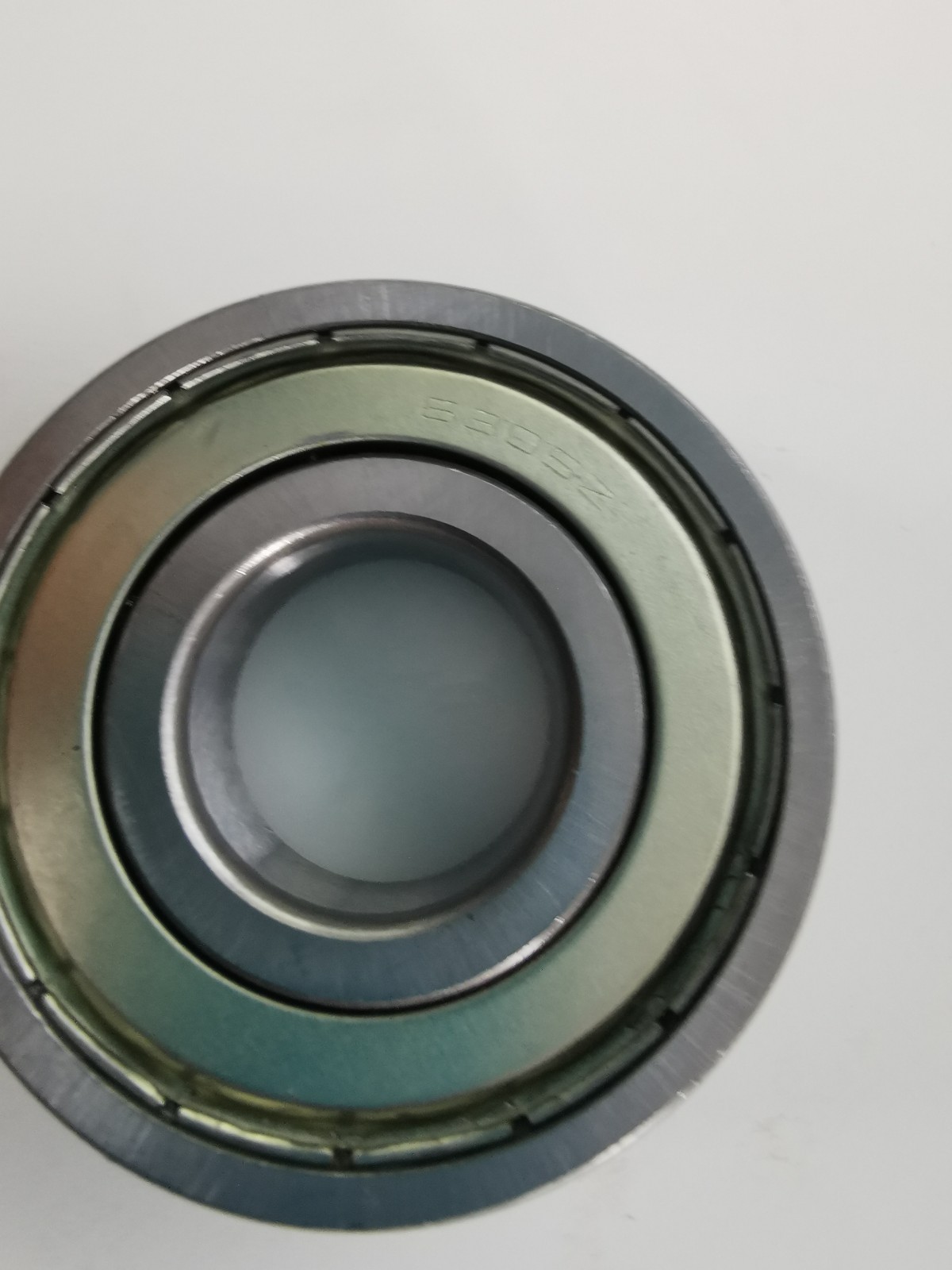 s-l1600-1169.jpg Close-up of a metal bearing showing inner and outer races, captured from the edge to reveal the circular components