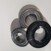 Close-up of metal bearing components: two inner race rings and a black rubber seal on a white surface