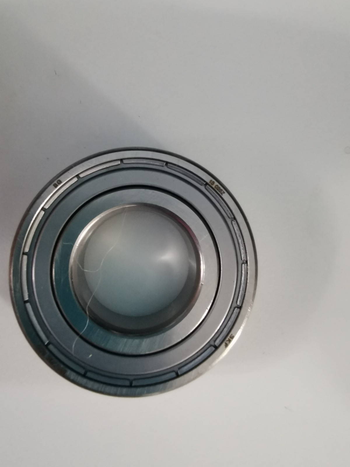 s-l1600-1176.jpg Close-up of a circular camera lens mount showing concentric metal rings and glass element on a light surface.