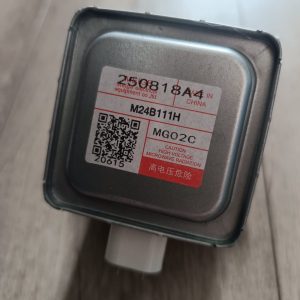 Close-up of a metal electronic component with a label showing model M24B11H and cautionary text about high voltage microwave radiation; contains a QR code and Chinese/English markings.