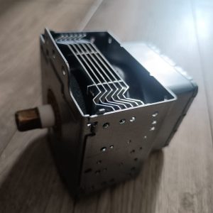 Close-up of a metal rectangular component with stacked thin fins inside, mounted on a wooden shaft.