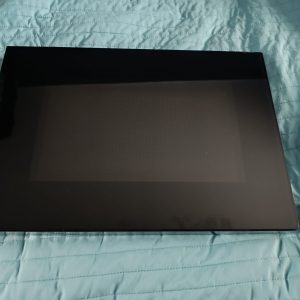 Closed black laptop resting on a teal quilted surface, with a metal stand visible at the right edge.