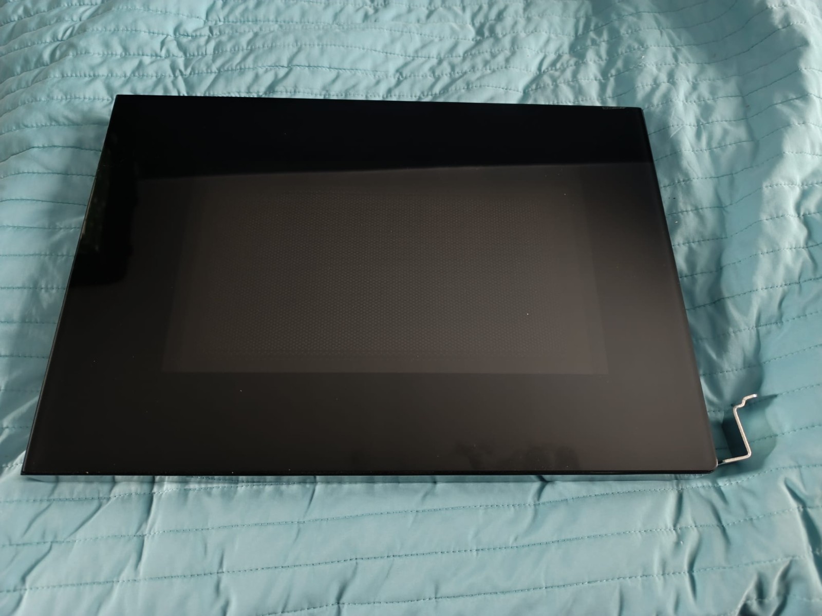 s-l1600-1232.jpg Closed black laptop resting on a teal quilted surface, with a metal stand visible at the right edge.