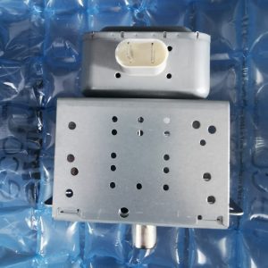 Metal rectangular mechanical component with a white two-pin plastic connector on top, mounted on a perforated metal housing against a blue padded background.