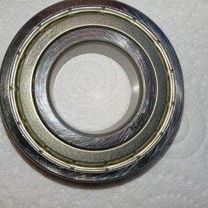 Close-up of a metal bearing race with inner and outer rings on a light background.