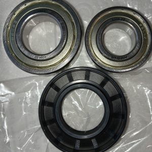 Three metal bearings laid on a plastic bag, two open-center ball bearings with stamped markings and a black-sealed bearing nearby