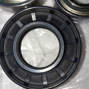 Close-up of a black bearing race with segmented, tab-like sections and an inner bore, resting on a plastic-covered surface.