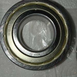 Close-up of a circular metal bearing with inner and outer races and a seal, resting on a gray textured surface