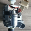 Disassembled appliance pump with motor, wires, and white plastic fittings