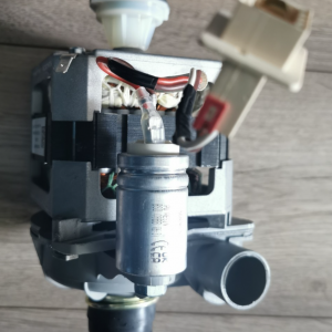 Disassembled appliance pump with motor, wires, and white plastic fittings