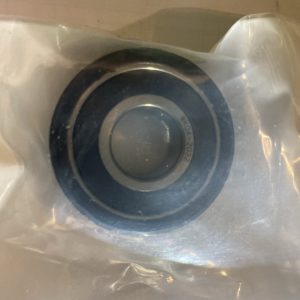 Close-up of a stainless steel sink drain with a black rubber gasket, wrapped in plastic protective film.