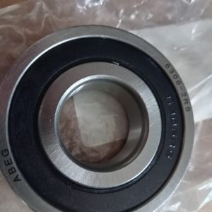 Close-up of a metal ball bearing with inner and outer races, resting on clear plastic wrap.