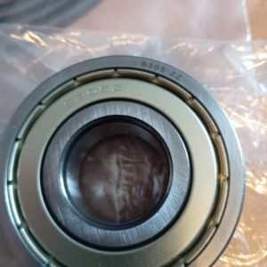 Close-up of a metal ball bearing with outer race, inner ring visible, engraved '6305 ZZ' (double shield).