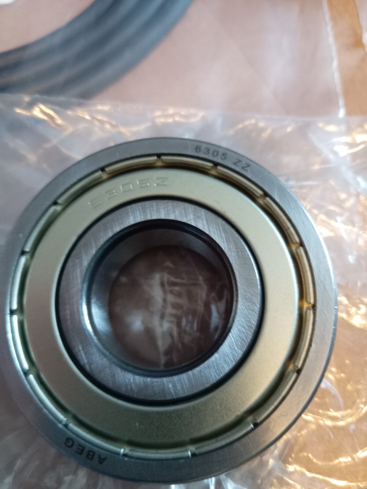 s-l1600-151.jpg Close-up of a metal ball bearing with outer race, inner ring visible, engraved '6305 ZZ' (double shield).