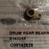 Small bronze drum rear bearing component with a circular hole and mounting tab resting on a labeled plastic bag