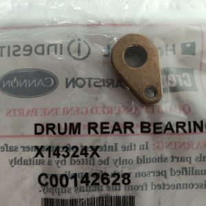 Small bronze drum rear bearing component with a large central hole and a smaller mounting hole, resting on its packaging that reads 'DRUM REAR BEARING' (inverted in the photo).