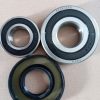 Three ball bearings of different sizes with metal outer rings and black seals on a brown background.