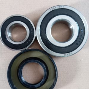 Three ball bearings of different sizes with metal outer rings and black seals on a brown background.