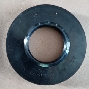 Black rubber oil seal with a metal inner ring, circular gasket on a brown surface.