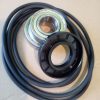 Coiled drive belt with a metal bearing and a black pulley resting on top, showing a circular metal race and inner hole.