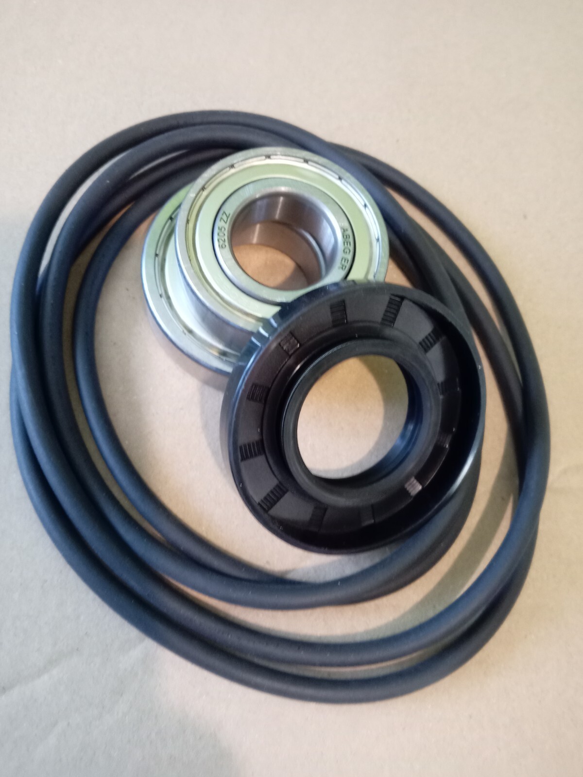 s-l1600-166.jpg Coiled drive belt with a metal bearing and a black pulley resting on top, showing a circular metal race and inner hole.