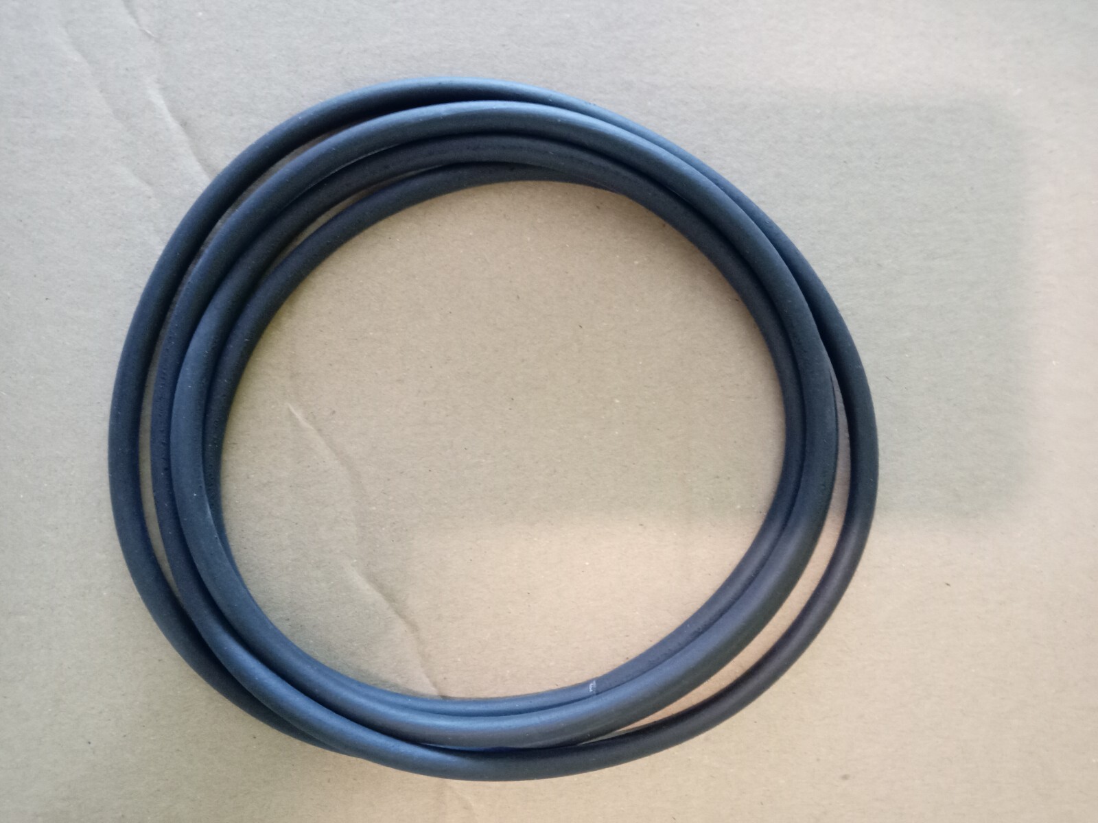 s-l1600-167.jpg Coiled black rubber electrical cable on a brown cardboard background in a neat circle