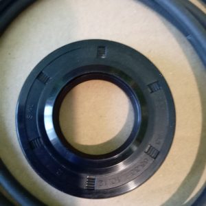 Close-up of a black circular mechanical ring with evenly spaced rectangular notches on a tan surface.