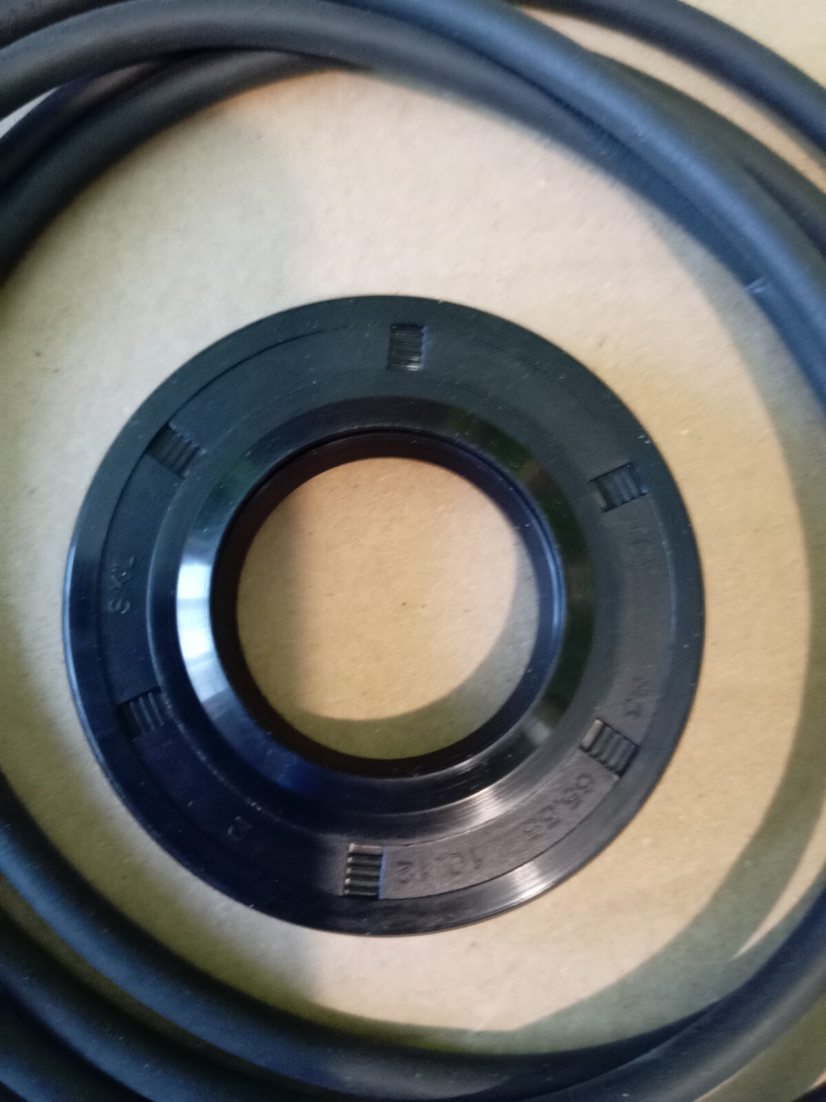 s-l1600-168.jpg Close-up of a black circular mechanical ring with evenly spaced rectangular notches on a tan surface.