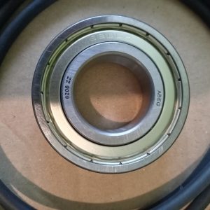 Close-up of a metal ball bearing (6206 ZZ) with inner and outer race visible on a brown surface. A black cable surrounds it.