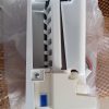 White plastic electrical module with a row of small vertical slots and a blue toggle/button on the lower left, wires visible on the right side
