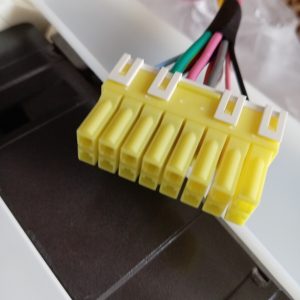 Close-up of a yellow, multi-pin connector block with several colored wires ready for wiring or power distribution