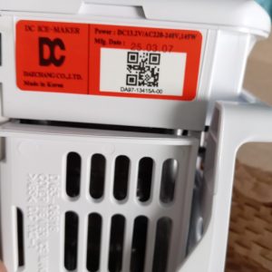 Close-up of a white device with a red label showing DC Maker branding, power spec, date, and a QR code.