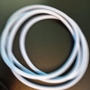 White charging/data cable coiled in a circular loop on a dark surface/desk