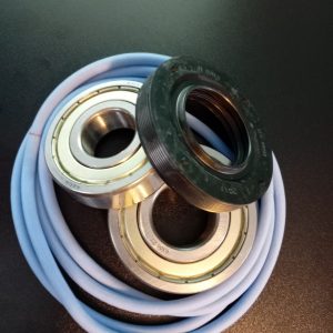 Close-up of metal ball bearing races with a black rubber seal resting on a coiled blue hose against a dark background