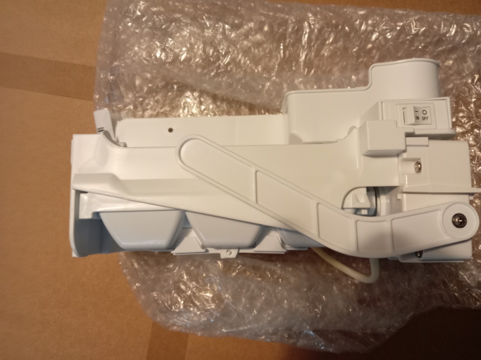 s-l1600-246.jpg Close-up of a white plastic mechanical part with a curved arm and an on/off switch, resting on bubble wrap in a box
