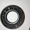 Close-up of a metal bearing: circular outer and inner races with evenly spaced segmented sections for rolling elements, used to allow smooth rotation.