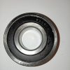 Metal ball bearing with inner and outer rings photographed on white surface. Text etched on outer race visible (e.g., 6306-2RS).