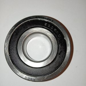 Metal ball bearing with inner and outer rings photographed on white surface. Text etched on outer race visible (e.g., 6306-2RS).