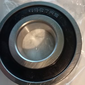 Close-up of a metal ball bearing (outer race) with stamped code resting on a plastic bag