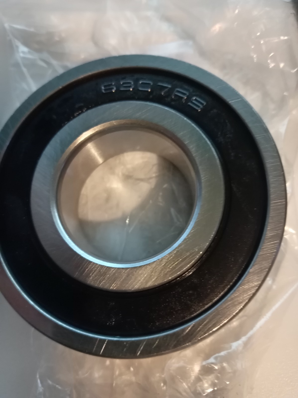 s-l1600-304.jpg Close-up of a metal ball bearing with 6307RS stamped on the outer ring, resting on plastic wrap.
