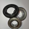 Assorted ball bearing races and a black rubber seal laid on a white surface for assembly.