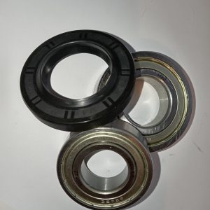 Assorted ball bearing races and a black rubber seal laid on a white surface for assembly.