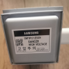 Samsung electrical component with a high-voltage danger label and QR code on a metal housing (Made in Malaysia).